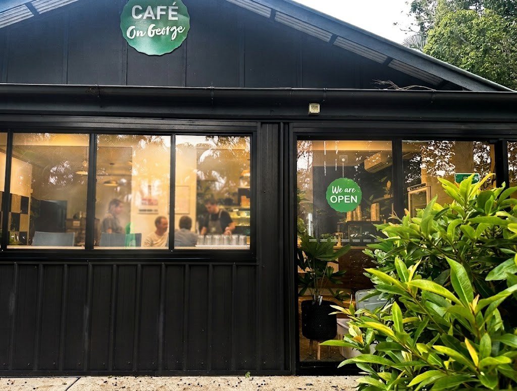 The exterior of Café on George, a STEPS Group social enterprise café, with illuminated windows and an open sign